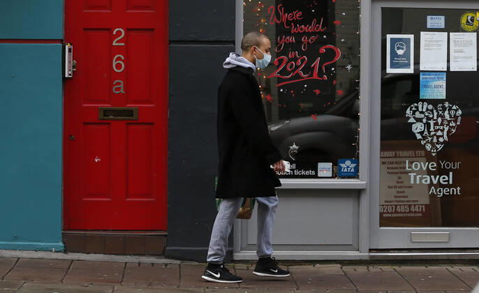 (210120) -- LONDON, Jan. 20, 2021 -- A man wearing a face mask walks past a closed travel agent shop with Where would you go in 2021? seen on the glass window in London, Britain, on Jan. 19, 2021. The number of people who have died within 28 days of a positive coronavirus test has surpassed the grim milestone of 90,000 in Britain after another 1,610 were confirmed, according to official figures released Tuesday. The latest daily death toll, the highest since the pandemic began in the country, brought the total number of coronavirus-related deaths in Britain to 91,470, the data showed. ) BRITAIN-LONDON-COVID-19-DEATH TOLL HanxYan