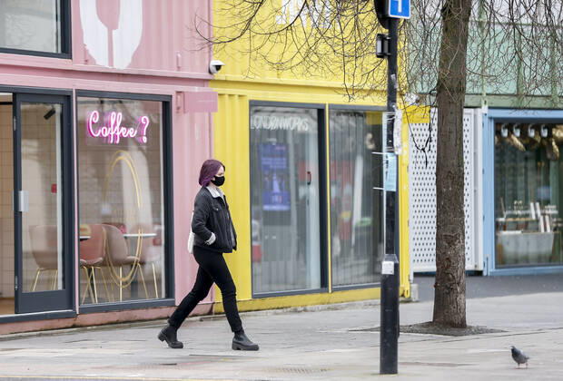 (210120) -- LONDON, Jan. 20, 2021 -- A woman wearing a face mask walks on the street in London, Britain, on Jan. 19, 2021. The number of people who have died within 28 days of a positive coronavirus test has surpassed the grim milestone of 90,000 in Britain after another 1,610 were confirmed, according to official figures released Tuesday. The latest daily death toll, the highest since the pandemic began in the country, brought the total number of coronavirus-related deaths in Britain to 91,470, the data showed. ) BRITAIN-LONDON-COVID-19-DEATH TOLL HanxYan
