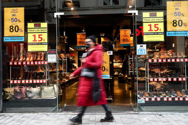 (210123) -- BRUSSELS, Jan. 23, 2021 -- A woman wearing a face mask walks past a shop with sales posters in Brussels, Belgium, Jan. 22, 2021. The annual Belgian winter sales kicked off on Jan. 4. To boost consumption, the scheduled four-week-long winter sales have been extended by two weeks until Feb. 15. ) BELGIUM-BRUSSELS-COVID-19-WINTER SALES ZhangxCheng 