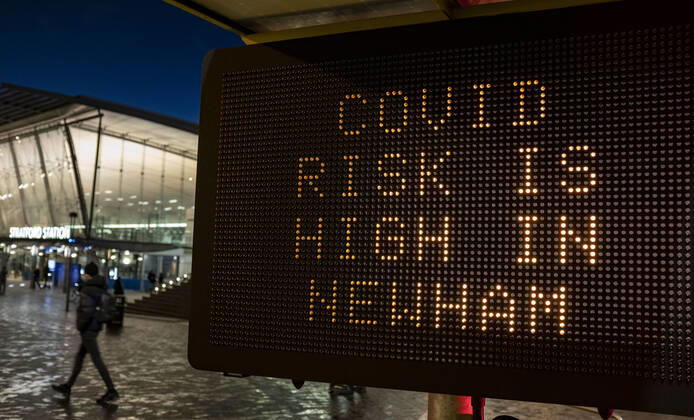 January 23, 2021, London, United Kingdom: A person passing the COVID sign read â€oeCovid risk is high in Newham†in Stratford, the London Borough of Newham, England, UK on January 23, 2021. Some of England s Covid hotspots are still in London Hounslow, Ealing, Brent, Barking and Dagenham and Newham are the boroughs which fall in the country s top 10 for worst case rates. London United Kingdom - ZUMAj323 20210123_zip_j323_015 Copyright: xMayxJamesx