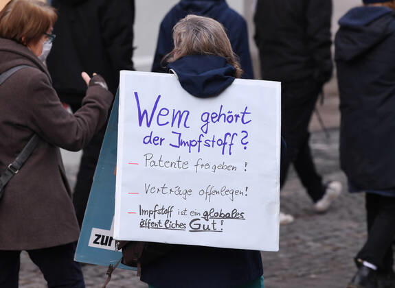 Tuebingen 23.01.2021 Themenbild, Demonstrantin mit Banner in der Tuebinger Innenstadt: Wem gehoert der Impfstoff? Patente freigeben! Vertraege offenlegen! Impfstoff ist ein globales, oeffentliches Gut!