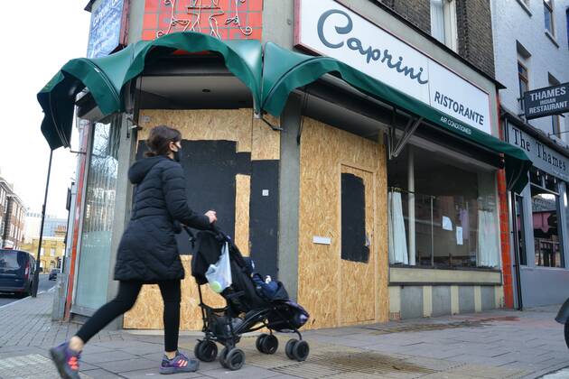 January 23, 2021, London, United Kingdom: Woman wearing a face mask with a stroller walks past a closed and boarded up restaurant, near Waterloo Station during the third national lockdown..Prime Minister Boris Johnson announced that there was evidence that the new variant of the coronavirus is more deadly. London United Kingdom - ZUMAs197 20210123_zaa_s197_142 Copyright: xThomasxKrychx