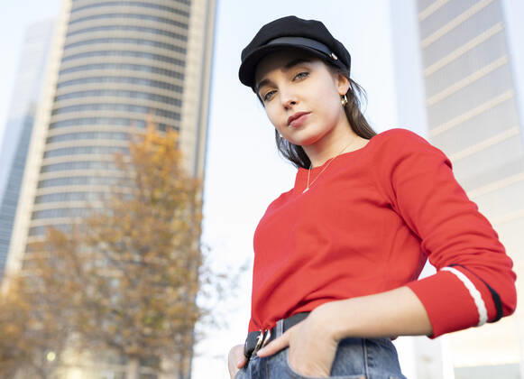 Young woman with hands in pockets standing against building model released Symbolfoto JCCMF00223