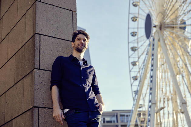 Thoughtful businessman standing with hands in pockets against wall and ferris wheel in city model released Symbolfoto RHF02584
