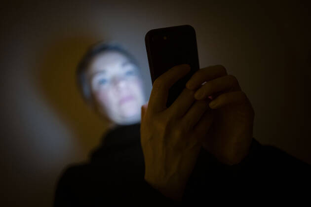 IMAGO Creative: Kulturelle Folgen der Pandemie: Gesundheitsbewußtsein und Alleinsein Symbolfoto zum Thema Handysucht: Eine Frau schaut in einem dunklen Raum auf ihr Smartphone. Berlin, 23.01.2021 Berlin Deutschland