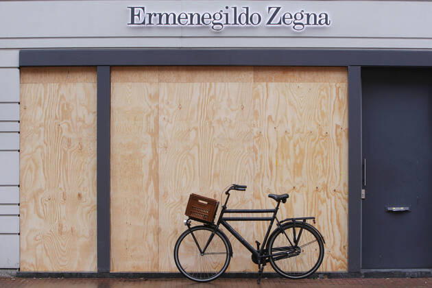 A bicycle parked in front of the Ermennegildo Zegna store building are protected with plywood siding to prevent vandalism by anti-coronavirus measure protestors at the Pieter Cornelisz Hooftstraat luxury shopping street on January 28, 2021 in Amsterdam, Netherlands. Several cities in the Netherlands have been riddled with demonstrations and vandalism reaction to the curfew that has been installed by the Dutch government to avoid the spread of the coronavirus. Amsterdam Netherlands Copyright: xPauloxAmorimx amp20210128_002