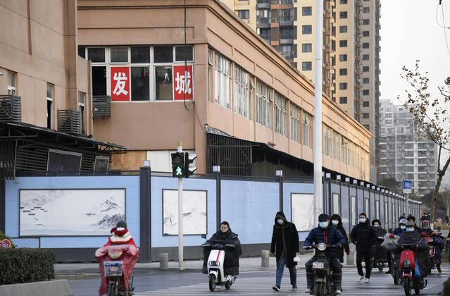 WHO probe into coronavirus origins in Wuhan People wearing face masks walk and ride motorcycles past the Huanan seafood wholesale market in Wuhan, China, on Jan. 29, 2021. A full-fledged investigation by experts from the World Health Organization is under way in the city, where the novel coronavirus was first detected in late 2019. 