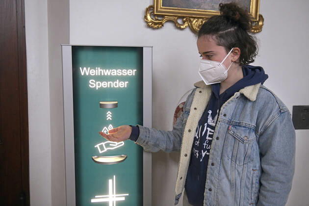News Bilder des Tages 30.01.2021, Kirchen in Bayern, Corona-Regeln in einer Kirche in Bayern, Eine junge Kirchenbesucherin mit Mundschutz lässt sich Weihwasser vom Automatischen Spender auf die Hand geben. (Modelreleased) Der von der Mindelheimer Firma Elektro-Bauer neuentwickelte, Corona-Konforme Weihwasser-Spender mit berührungslosem Ultraschall-Bewegungs-Sensor sichert die Einhaltung der Hygienemassnahmen für die Gläubigen. 30.01.2021, Kirche in Corona-Zeiten 30.01.2021, Kirche in Corona-Zeiten