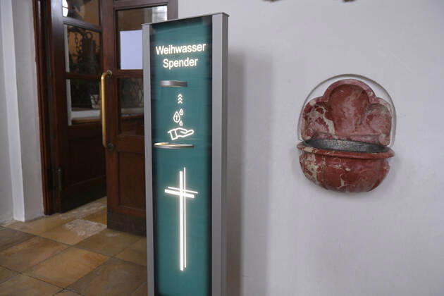 30.01.2021, Kirchen in Bayern, Corona-Regeln in einer Kirche in Bayern, EIn von der Mindelheimer Firma Elektro-Bauer neuentwickelter, Corona-Konformer Weihwasser-Spender mit berührungslosem Ultraschall-Bewegungs-Sensor sichert die Einhaltung der Hygienemassnahmen für die Gläubigen. Weihwasser kann man sich vom Automatischen Spender auf die Hand geben lassen. Rechts an der Wand der alte Weihwasserkessel der in Zeiten Corona stillgelegt wurde. 30.01.2021, Kirche in Corona-Zeiten 30.01.2021, Kirche in Corona-Zeiten