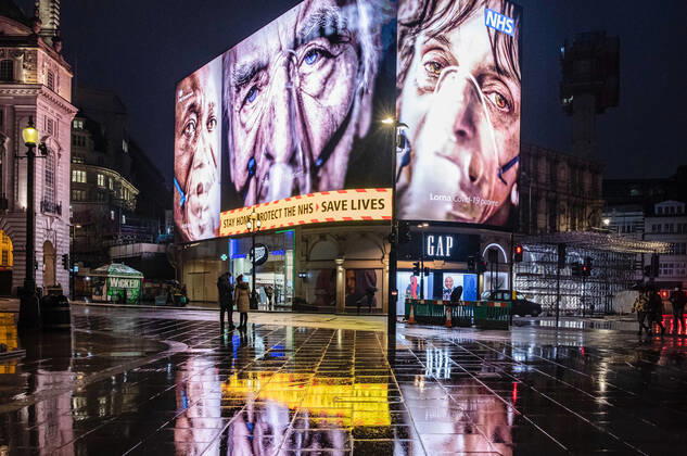 January 31, 2021, London, United Kingdom: Silhouette of pedestrians walking past a COVID-19 electronic billboard encouraging people to stay home, protect the NHS, save lives..Department of Health and Social Care recorded a total of 3,817,176 infections, 106,158 death and 1,673,936 recovered since the beginning of the outbreak. London United Kingdom - ZUMAs197 20210131_zaa_s197_178 Copyright: xMayxJamesx