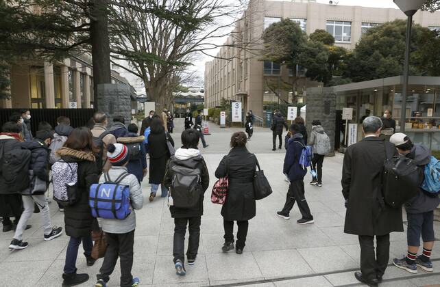 Japan s private junior high school entrance exams Students walk with a parent to the venue of their entrance exam at a private junior high school in Tokyo on Feb. 1, 2021. Entrance exams to private junior high school began the same day in Tokyo for enrollment in the coming spring, with anti-coronavirus measures being taken, such as checking students temperatures at the entrance. 