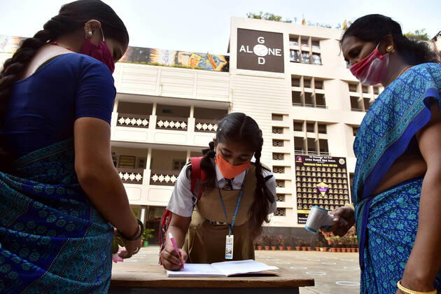 (210201) -- HYDERABAD, Feb. 1, 2021 -- A student signs on a book before entering a school after a gap of almost a year following COVID-19 guidelines in Hyderabad, capital of India s southern state of Telengana on Feb. 1, 2021. (Str Xinhua) INDIA-HYDERABAD-SCHOOL REOPENS ParthaxSarkar 
