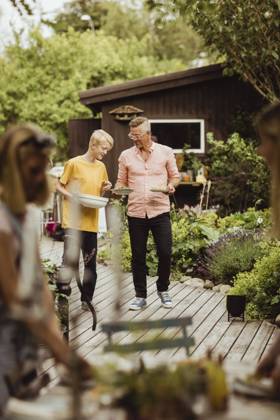 IMAGO Creative: Landleben - Essen Father and son walking with bowl and plate in back yard during social event Sweden, Gothenburg, model released, property released Copyright: xMaskotx , MA83799