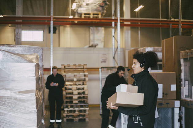 IMAGO Creative: Kreative Renaissance -- der junge Entrepreneur Female entrepreneur holding packages standing by colleagues at logistics warehouse Sweden, Stockholm, model released, property released Copyright: xMaskotx , MA84082