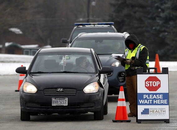 A health care worker checks in people as they arrive by car to recieve their Moderna coronavirus vaccine in Medina, Ohio, Thursday, February 4, 2021.  CLE20200204125 AARONxJOSEFCZYK