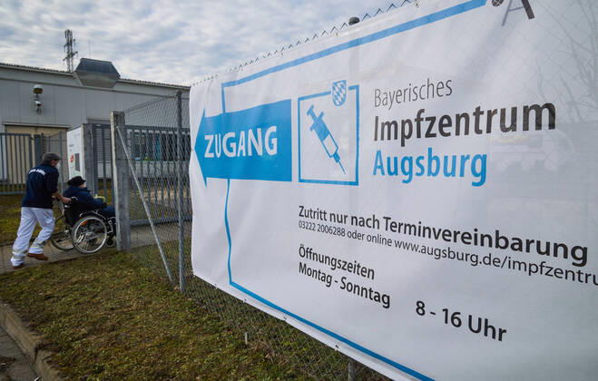 Zugang zum Impfzentrum, eine Person im Rollstuhl wird zum Impfzentrum geschoben; Bayerisches Impfzentrum Augsburg, Presseführung; Bayerisches Impfzentrum Augsburg, Presseführung;
