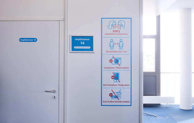 Hinweis-Schilder vor einem Impfzimmer im Impfzentrum; Bayerisches Impfzentrum Augsburg, Presseführung; Bayerisches Impfzentrum Augsburg, Presseführung;