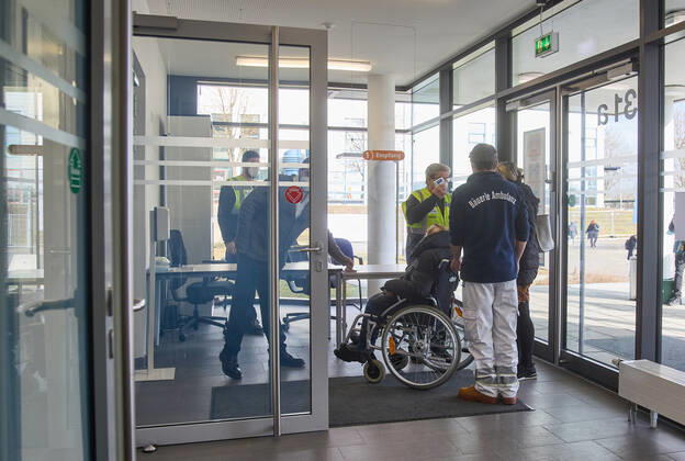 Eingangsbereich im Impfzentrum, Temperaturmessung; Person im Rollstuhl; Bayerisches Impfzentrum Augsburg, Presseführung; Bayerisches Impfzentrum Augsburg, Presseführung;