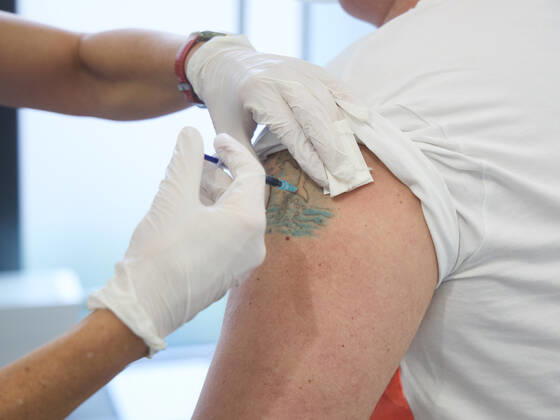 Impfung eines Mannes mittleren Alters, Impfung erfolgt in eine ungefärbte Stelle in einem Tattoo, Bayerisches Impfzentrum Augsburg, Presseführung; Bayerisches Impfzentrum Augsburg, Presseführung;