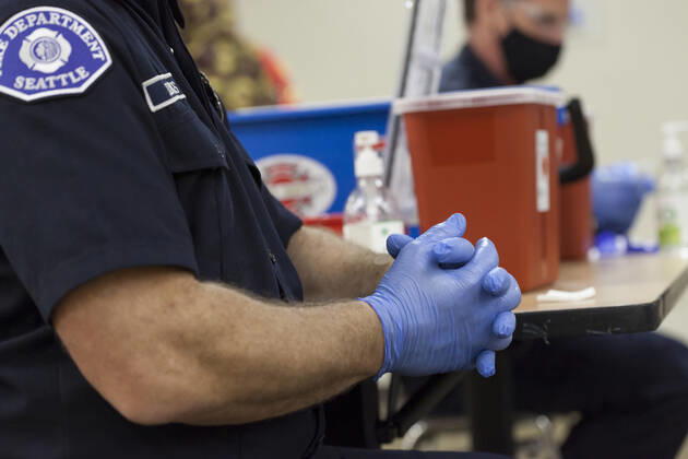 February 5, 2021, Seattle, Washington, USA: Members of the Seattle Fire Department apply hand sanitizer to their gloves as they wait for the next patient at the Ethiopian Community of Seattle in the Rainier Valley on Friday, February 5, 2021. To date, the Seattle Fire Department Mobile Vaccination Teams have vaccinated 2,436 vulnerable Seattle residents and workers since launching its vaccination effort on January 14, 2021. Seattle USA - ZUMAg235 20210205_zap_g235_010 Copyright: xPaulxChristianxGordonx