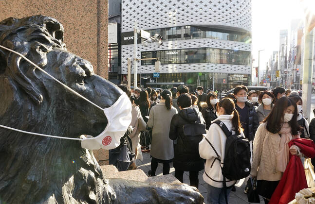 News Bilder des Tages New coronavirus in Japan People wearing face masks walk in front of a masked lion statue in Tokyo s Ginza area on Feb. 7, 2021, amid the coronavirus pandemic. 