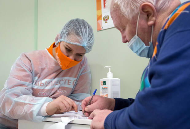 SEVASTOPOL, RUSSIA - FEBRUARY 8, 2021: A volunteer helps a patient to fill out a form before vaccination with the Gam-COVID-Vak (Sputnik V) vaccine against COVID-19 at Dasha Sevastopolskaya Hospital No 5. Starting February 8, Sevastopol starts a mass COVID-19 vaccination campaign; earlier, the vaccine was available to medical workers and teachers only. Sergei Malgavko TASS  TS0F6438