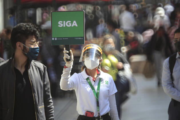 February 9, 2021, Mexico City, Mexico City, Mexico: A officer holds a sign to people follow the rules to prevent agglomerations. The Mexican Government allowed the reopening of stores, some shops make outside sell to prevent crowd of people, as an attempt to prevent spread of the Virus February 9, 2021 in Mexico City, Mexico Mexico City Mexico - ZUMAe321 20210209_zia_e321_028 Copyright: xAngelxMoralesxRizox