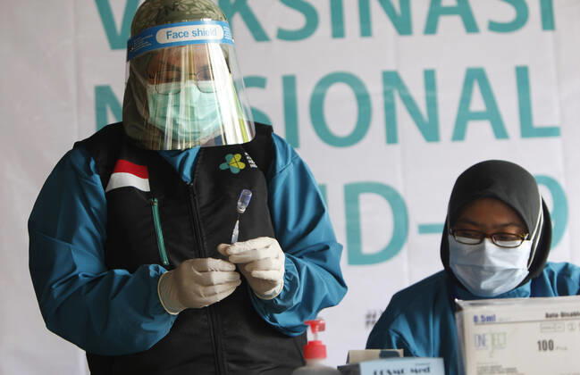 Indonesia s COVID-19 Mass Vaccination A health worker prepares vaccinates her colleague during COVID-19 mass vaccination for medical workers and elderly health workers in Bogor, West Java on February 11, 2021. (Photo by Adrian INA Photo Agency) 