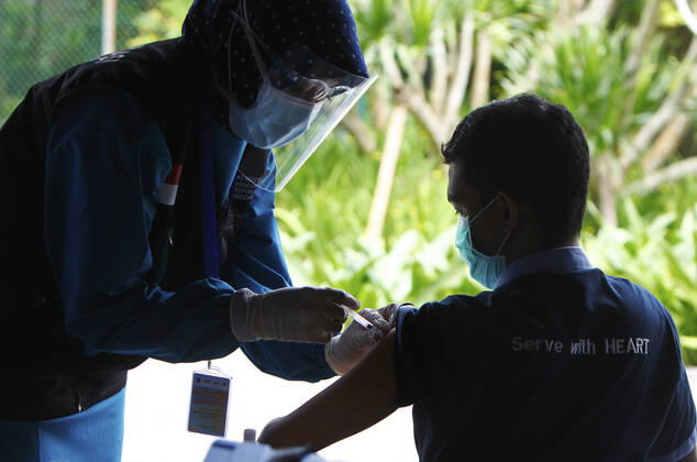 Indonesia s COVID-19 Mass Vaccination A health worker vaccinates her colleague during COVID-19 mass vaccination for medical workers and elderly health workers in Bogor, West Java on February 11, 2021. (Photo by Adrian INA Photo Agency) 