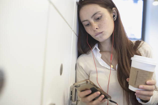 Young woman having a conversation on her smart phone holding a coffee cup in an office. model release HEX17003_TP_9404 Copyright: xTOBIASxPRASSEx