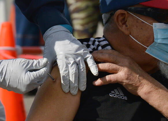 A local resident receives a COVID-19 vaccination shot at the South Park Recreation Center in Los Angeles on Thursday, February 11, 2021. To boost vaccination among people of color, L.A. county plans more sites, better messaging and access to transit. Black, Latino and Native American seniors are being vaccinated at lower rates than other groups.  LAP2021021121 JIMxRUYMEN