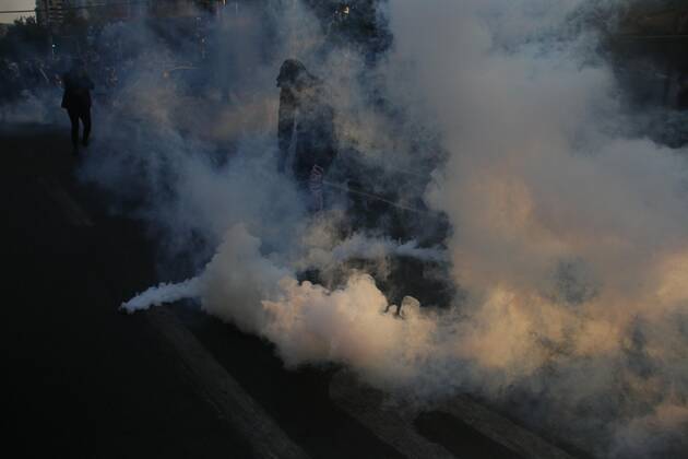 A protester walks between a tear gas bomb thrown by the Police during a demonstration in Plaza Italia in Santiago, Chile, 12 February 2021. The Chilean capital this Friday experienced a new day of protests against the government of President Sebastian Pinera and in rejection of police abuse after the death of juggler Francisco Martinez, shot dead by the Carabineros (militarized police) in a routine identity check. The death of the artist rekindled criticism of the Carabineros and demands to refound the police force. Santiago de Chile lives a new day of protests against the Government and the Carabineros !ACHTUNG: NUR REDAKTIONELLE NUTZUNG!  Copyright: xSebastianxSilvax AME5443 20210213-637487795839250505