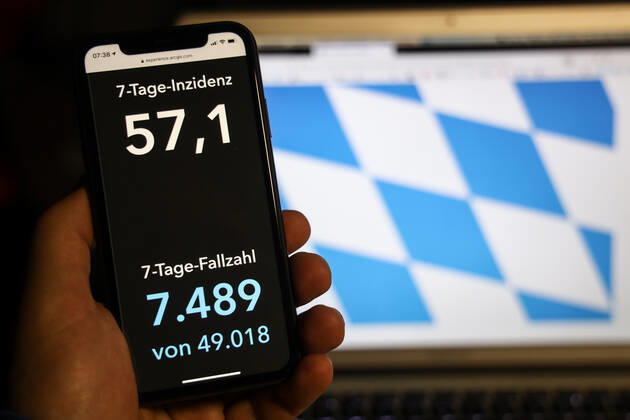 Coronavirus in Deutschland - Covid-19-Dashboard des Robert Koch-Institut DEU, Deutschland, Bayern, 15.02.2021: Die 7-Tage-Inzidenz (Fälle letzte 7 Tage 100.000 EW) wird auf einem iPhone angezeigt, im Hintergrund die Landesflagge