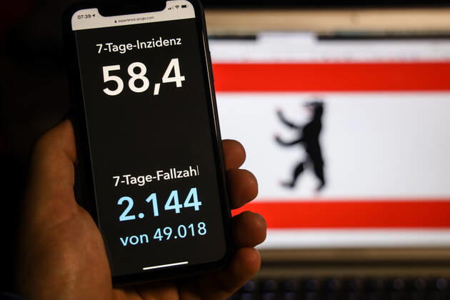 Coronavirus in Deutschland - Covid-19-Dashboard des Robert Koch-Institut DEU, Deutschland, Berlin, 15.02.2021: Die 7-Tage-Inzidenz (Fälle letzte 7 Tage 100.000 EW) wird auf einem iPhone angezeigt, im Hintergrund die Landesflagge