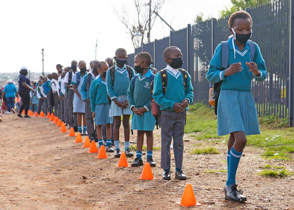 News Bilder des Tages (210216) -- JOHANNESBURG, Feb. 16, 2021 -- Pupils wait in line to get their body temperature checked at the gate of a primary school in Johannesburg, South Africa, Feb. 15, 2021. Over 20,000 public schools in South Africa were reopened in accordance with strict adherence to the COVID-19 protocol on Monday. (Photo by Xinhua) SOUTH AFRICA-JOHANNESBURG-COVID-19-PUBLIC SCHOOL-REOPEN MatthewxMartinxBrink 