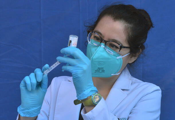 A physician assistant prepares a syringe from a vial of the Moderna vaccine for local residents waiting in line to receive a COVID-19 vaccination shot at the Kedren Community Health Center in South Los Angeles on Tuesday, February 16, 2021. To boost vaccination among people of color, L.A. county plans more sites, better messaging and access to transit. Black, Latino and Native American seniors are being vaccinated at lower rates than other groups.  LAP2021021612 JIMxRUYMEN