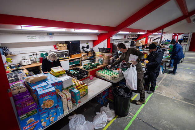 Volunteers help pack food at the FC United Foodhub for distribution amongst residents and vulnerable groups affected by the Coronavirus pandemic, on 19 February 2021. The food bank is situated at Broadhurst Park, home of non-league football team FC United of Manchester. Broadhurst Park is situated in the Moston area of the city, where a new strain of the Coronavirus, E484K, has been detected in the community over the past few days. The club has been shortlisted in the Football Supporters™ Association Lockdown Heroes Awards for 2020. Moston Greater Manchester England Broadhurst Park  Copyright: xMattxWilkinsonx
