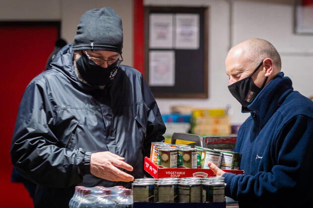 Volunteers help pack food at the FC United Foodhub for distribution amongst residents and vulnerable groups affected by the Coronavirus pandemic, on 19 February 2021. The food bank is situated at Broadhurst Park, home of non-league football team FC United of Manchester. Broadhurst Park is situated in the Moston area of the city, where a new strain of the Coronavirus, E484K, has been detected in the community over the past few days. The club has been shortlisted in the Football Supporters™ Association Lockdown Heroes Awards for 2020. Moston Greater Manchester England Broadhurst Park  Copyright: xMattxWilkinsonx