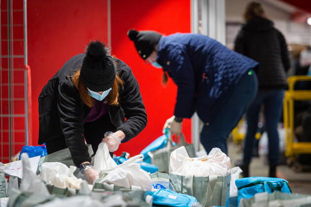 Volunteers help pack food at the FC United Foodhub for distribution amongst residents and vulnerable groups affected by the Coronavirus pandemic, on 19 February 2021. The food bank is situated at Broadhurst Park, home of non-league football team FC United of Manchester. Broadhurst Park is situated in the Moston area of the city, where a new strain of the Coronavirus, E484K, has been detected in the community over the past few days. The club has been shortlisted in the Football Supporters™ Association Lockdown Heroes Awards for 2020. Moston Greater Manchester England Broadhurst Park  Copyright: xMattxWilkinsonx