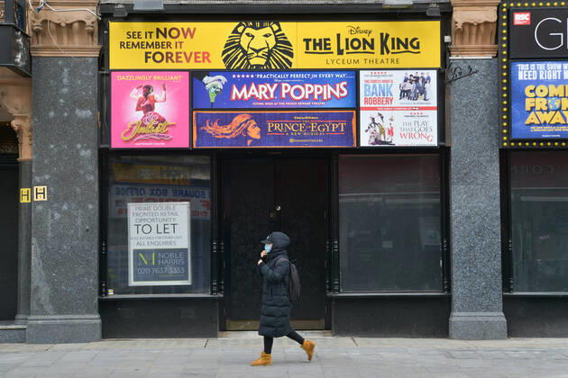 February 19, 2021, London, United Kingdom: A woman wearing a face mask as a precaution against the spread of covid-19 walking past the Lion King, permanently closed-down venue ticket sales shop in Central London..Covid-19 cases continue to drop in the UK, as the government continues to fight the spread of the virus as lockdown stays in Central London. London United Kingdom - ZUMAs197 20210219_zaa_s197_139 Copyright: xThomasxKrychx