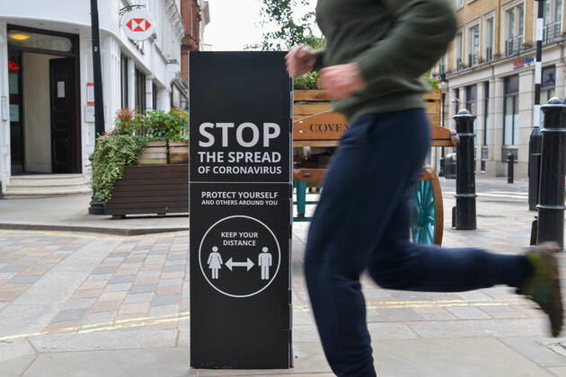 February 19, 2021, London, United Kingdom: A jogger passing by a covid-19 warning sign in Covent Garden, Central London..Covid-19 cases continue to drop in the UK, as the government continues to fight the spread of the virus as lockdown stays in Central London. London United Kingdom - ZUMAs197 20210219_zaa_s197_143 Copyright: xThomasxKrychx