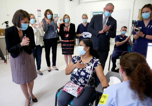 NSW COVID19 VACCINE ROLLOUT, Gayathry Vellangalloor Srinivasan, an Environmental Services Supervisor, is watched by NSW Premier Gladys Berejiklian (left), NSW Chief Medical Health Officer Kerry Chant (fifth right) and NSW Health Minister Brad Hazzard (third right) as she receives the states first Pfizer vaccination at the Royal Prince Alfred Hospital Vaccination Hub in Sydney, Monday, February 22, 2021. Australia will begin its roll out of the Pfizer coronavirus vaccine on Monday, the country s most complicated logistical exercise to date. ( NO ARCHIVING, EDITORIAL USE ONLY, NO USE IN BOOKS WITHOUT CONSENT SYDNEY NSW AUSTRALIA Copyright: xTobyxZernax 20210222001522236535