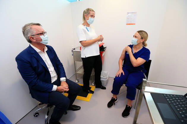 VIC COVID19 VACCINE ROLLOUT, Covid screening nurse Grace Gibney (right) receives one of the first Pfizer coronavirus vaccines from Nurse practitioner Sonja Elia as Health Minister Martin Foley (left) watches on at Austin Health in Melbourne, Monday, February 22, 2021. Australia will begin its roll out of the Pfizer coronavirus vaccine on Monday, the country s most complicated logistical exercise to date. ( NO ARCHIVING, EDITORIAL USE ONLY, NO USE IN BOOKS WITHOUT CONSENT MELBOURNE VIC AUSTRALIA Copyright: xMARKxSTEWARTx 20210222001522293459
