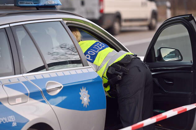 Grenzkontrollen an der oesterreichisch deutschen Grenze ,Grenzuebergang Kiefersfelden Grenzpolizisten kontrollieren Autofahrer bei der Einreise von Tirol Oesterreich nach Bayern Deutschland. Polizistin mit gelber Warnwesten beugt sich in ein Polizeiauto,