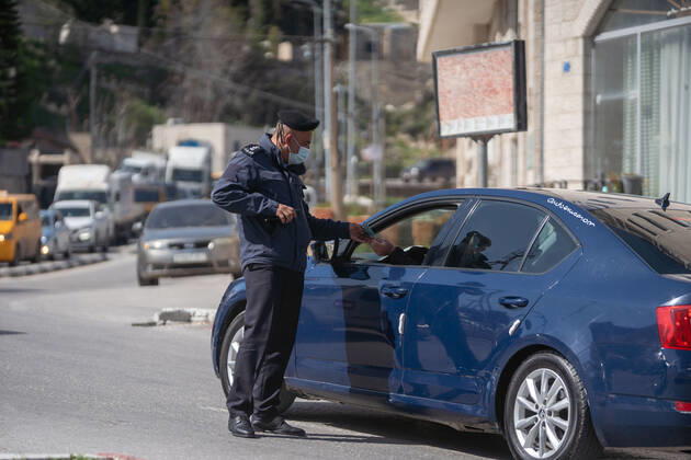 (210224) -- BETHLEHEM, Feb. 24, 2021 -- A Palestinian police officer works at a checkpoint on one of the main roads in Beit Sahour near the West Bank city of Bethlehem, Feb. 24, 2021. The Governor of Bethlehem announced the closure of Beit Sahour for 48-hours starting from 12:00 am Wednesday, after increase of the numbers of COVID-19 infections. (Photo by Xinhua) MIDEAST-BETHLEHEM-COVID-19-CHECKPOINT LuayxSababa 
