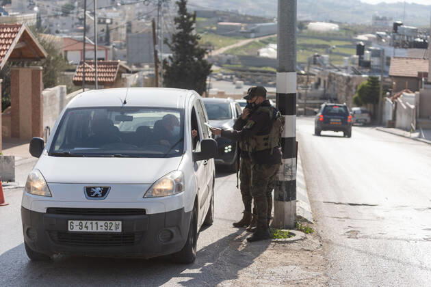 (210224) -- BETHLEHEM, Feb. 24, 2021 -- Palestinian police officers work at a checkpoint at one of the main roads of Beit Sahour near the West Bank city Bethlehem, Feb. 24, 2021. The Governor of Bethlehem announced the closure of Beit Sahour for 48-hours starting from 12:00 am Wednesday, after increase of the numbers of COVID-19 infections. (Photo by Xinhua) MIDEAST-BETHLEHEM-COVID-19-CHECKPOINT LuayxSababa 