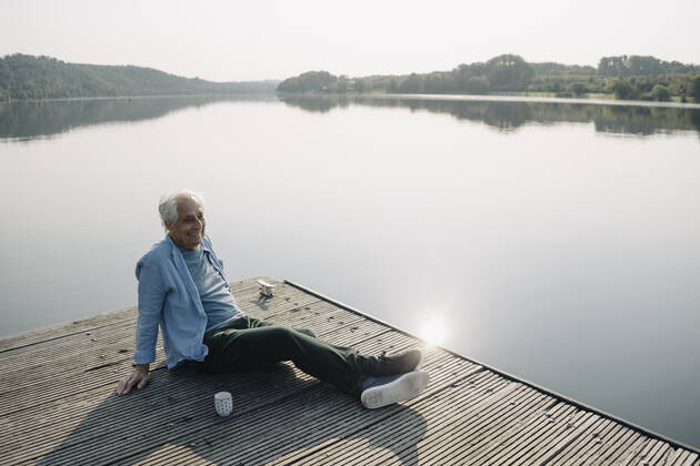 Smiling man looking away while relaxing on pier model released Symbolfoto GUSF05150