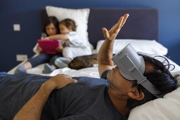 Man with virtual reality simulator gesturing while siblings using digital tablet on bed at home model released Symbolfoto property released IFRF00399