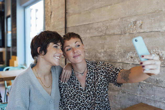 IMAGO Creative: Landleben - Essen Friends taking selfie on mobile phone while sitting at restaurant model released Symbolfoto property released JRVF00105