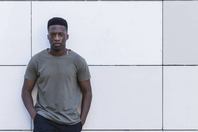 Young man with hands in pockets standing against white wall model released Symbolfoto PNAF00585